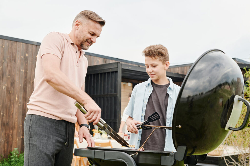 Father and son smiling and grilling food
