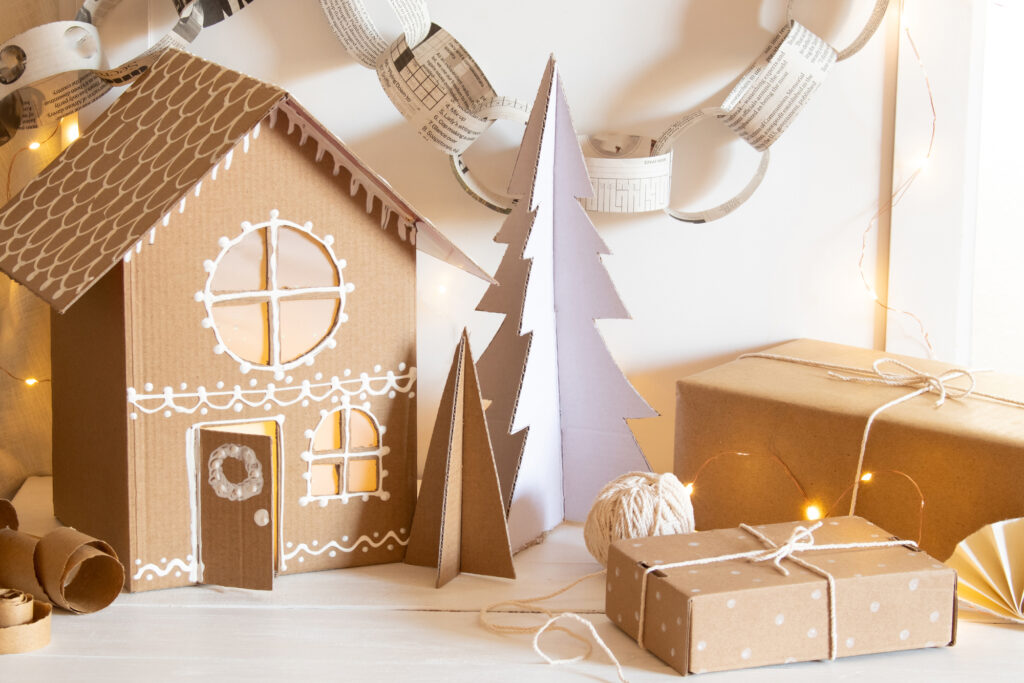 Holiday crafts made of repurposed household materials and gift wrap. A cardboard Christmas village, cardboard trees, paper chains and gifts wrapped with recycled paper grocery bags!