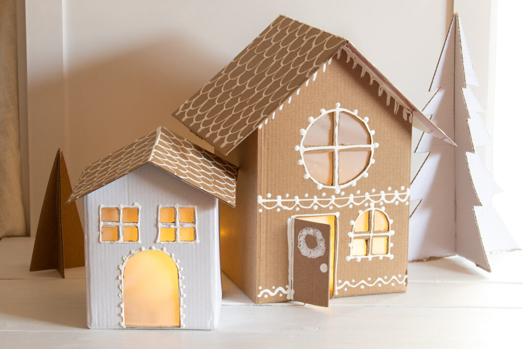 Turn your boxes into gingerbread houses and a Carboard Christmas village that will last for years made with a white paint pen and a pair of scissors!