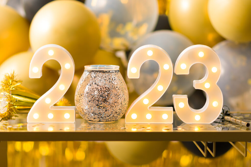 New Years party decorations on a tabletop spelling 2023 with a Scentsy wax warmer replacing the zero and gold balloons all around