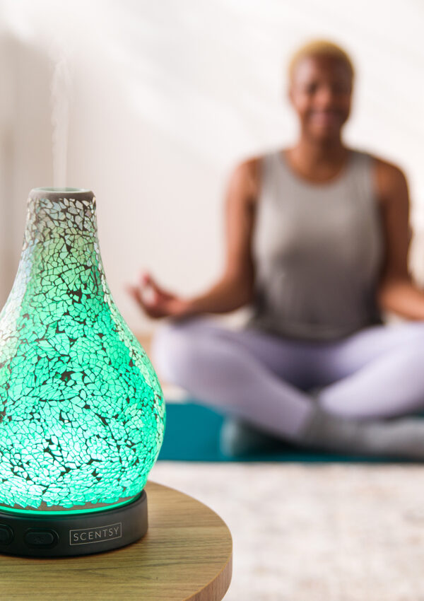 Woman meditating with a Scentsy oil diffuser and essential oils diffusing in the room for Mind Body Wellness day