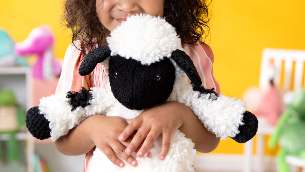 Little girl holding a Valley the Valais Blacknose Sheep Scentsy Buddy stuffed animal 
