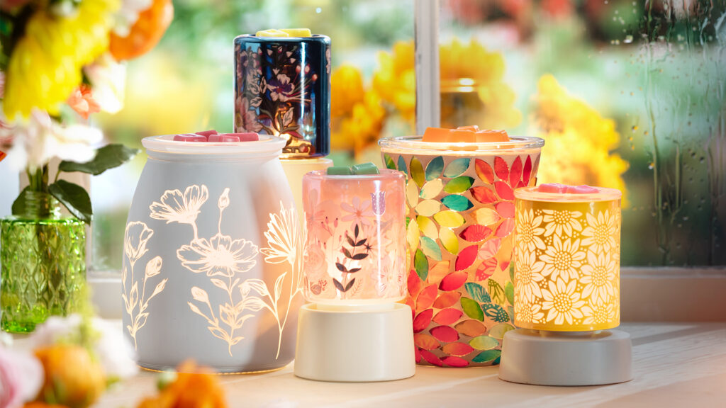 Scentsy wax warmers and mini warmers that have floral patterns and are inspired by may flowers. They are all lit up an melting scentsy wax cubes