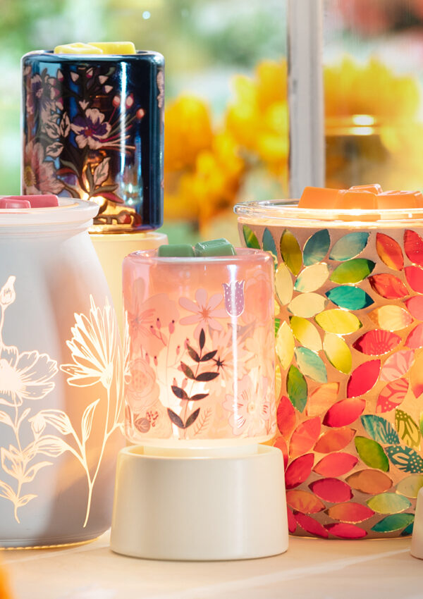 Scentsy wax warmers and mini warmers that have floral patterns and are inspired by may flowers. They are all lit up an melting scentsy wax cubes