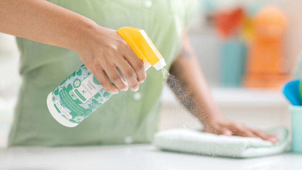 Scentsy counter clean being sprayed on the counter and wiped down with a white kitchen towel