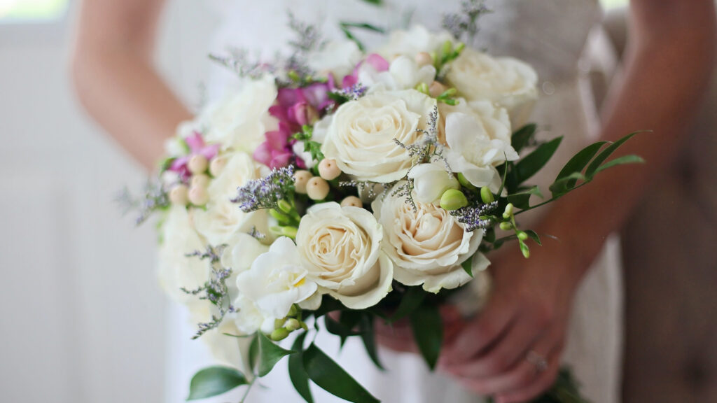 A brides hands holding a big flower bouquet 