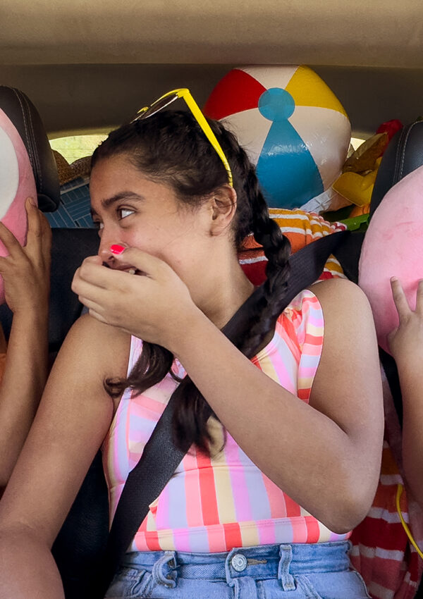 three kids sitting in the car on a road trip using the unicorn Scentsy buddy travel neck pillow