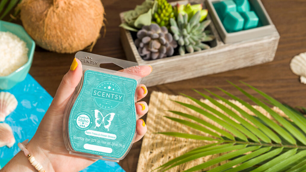 palm trees and ocean breeze scented wax melts being held by a hand with yellow painted nails