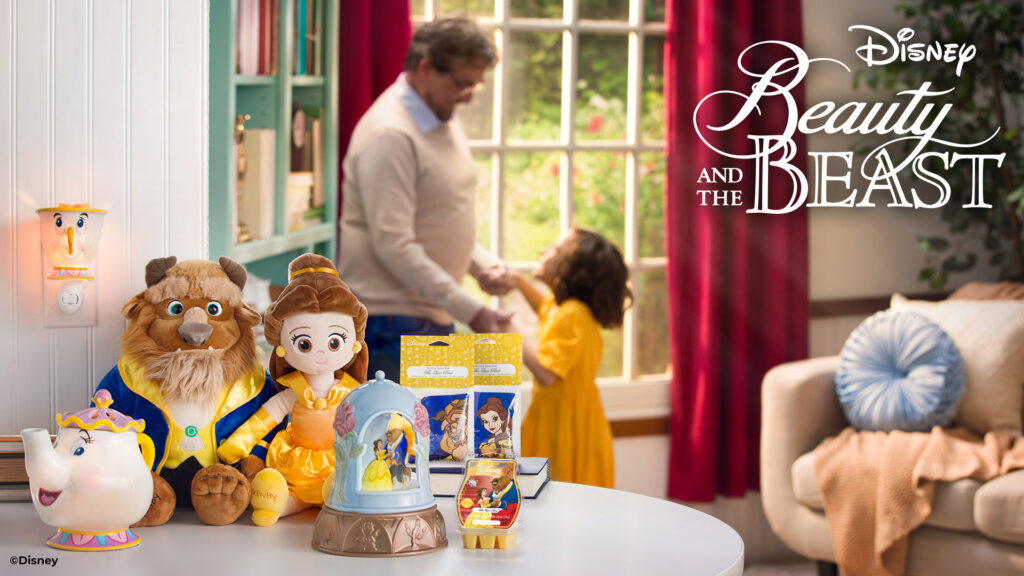 Disney Beauty and the Beast scent products from Scentsy sitting on a table with a father and his daughter dancing in the background wearing a Belle yellow dress