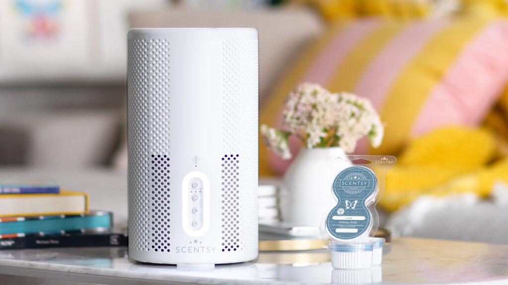 Scentsy air purifier and scentsy pods in Luna fragrance sitting on a table with books and flowers in a vase