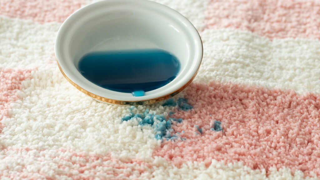 Blue wax spilling out of a wax warmer dish onto pink and white carpet