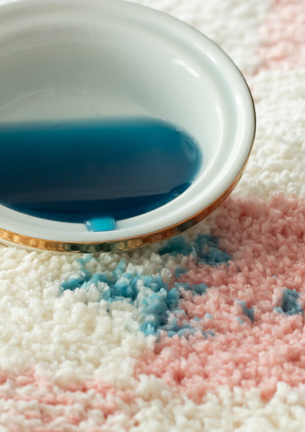 Blue wax spilling out of a wax warmer dish onto pink and white carpet
