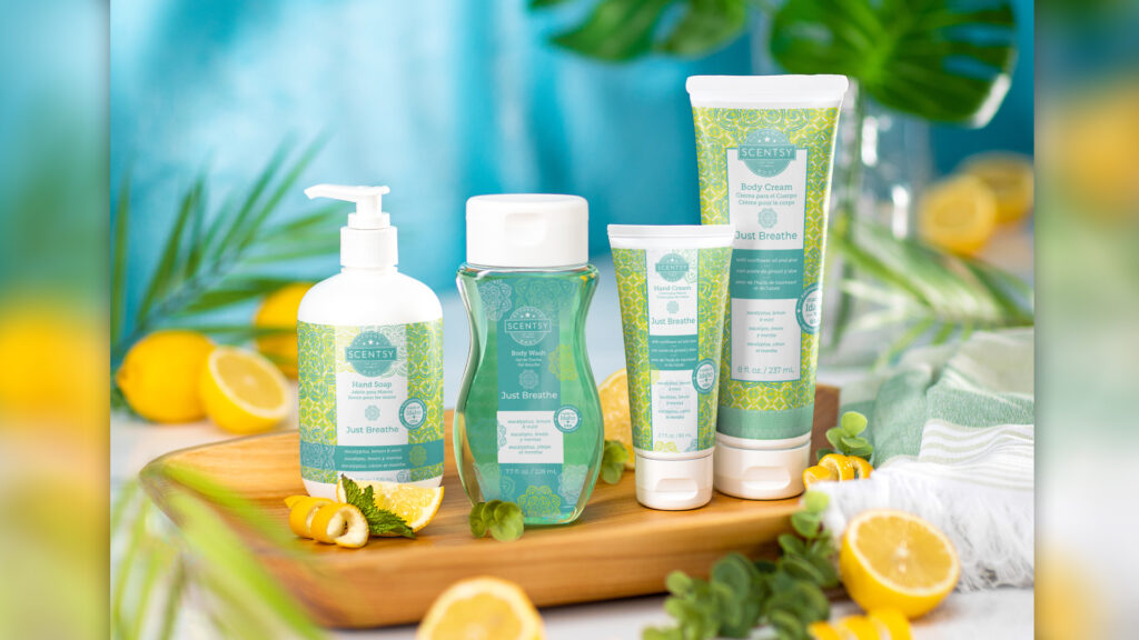 Just Breathe scented Scentsy body products sitting on a wooden plate with greenery, eucalyptus and lemons scattered around.