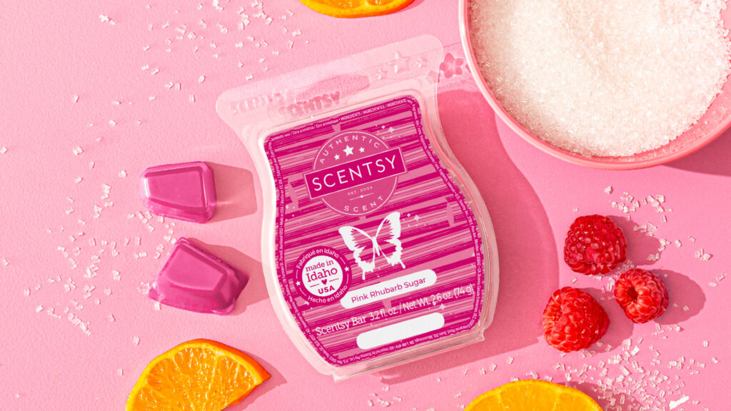 Pink rhubarb sugar scented Scentsy wax melts next to sugar, orange slices and raspberries