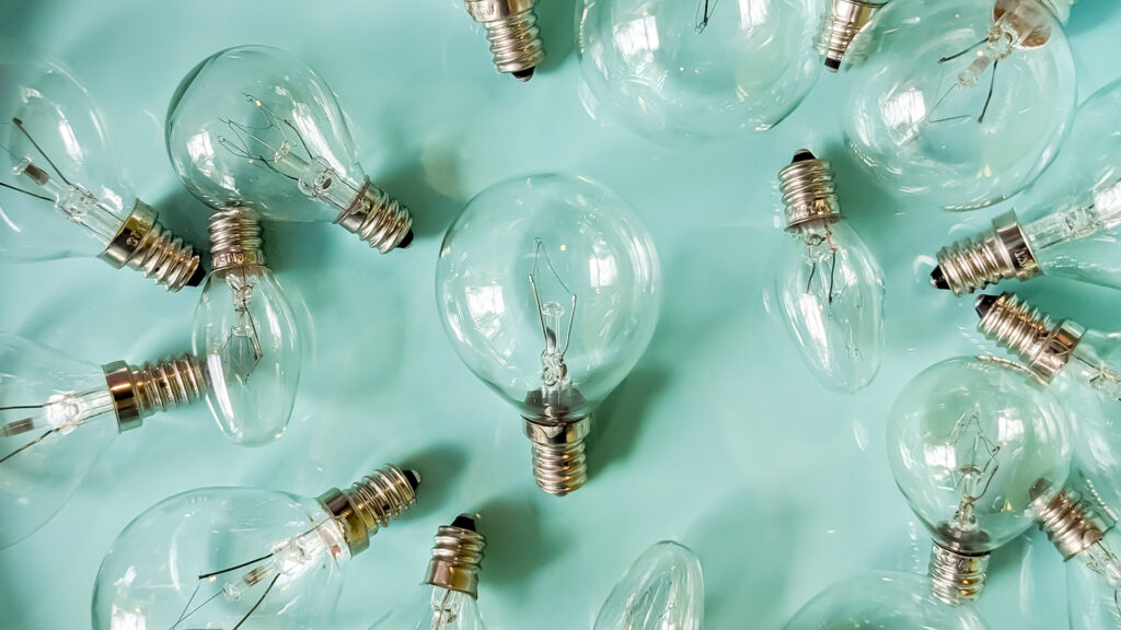 A bunch of lightbulbs scattered on a light blue back drop