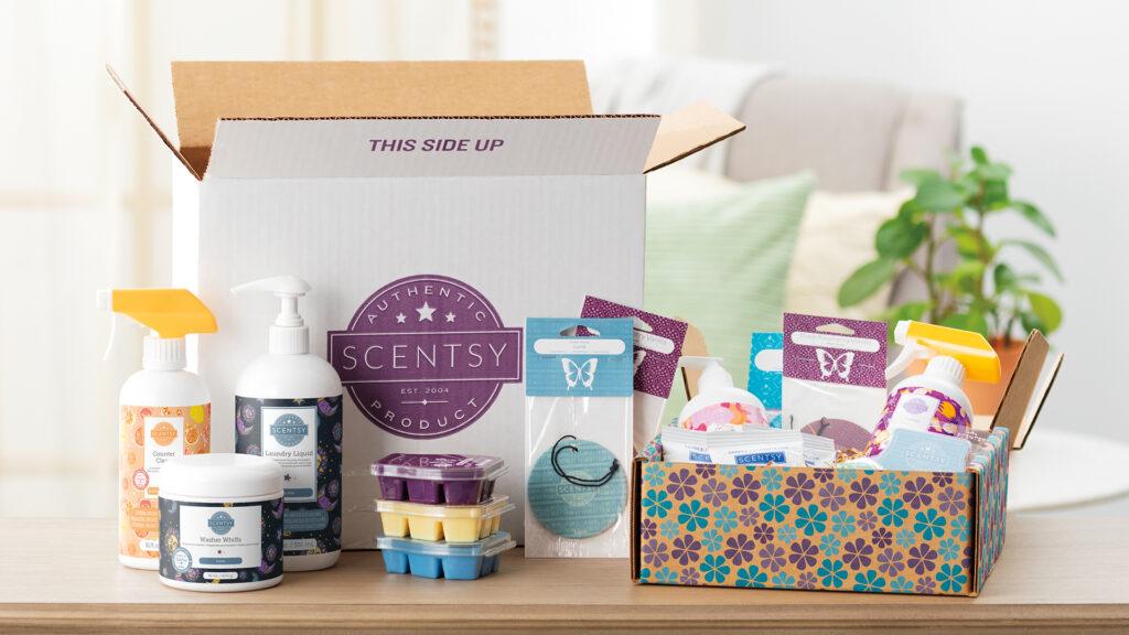 An opened cardboard package with the scent products from a Scentsy Club order sitting out including cleaning products, wax melts, scent circles and hand soap
