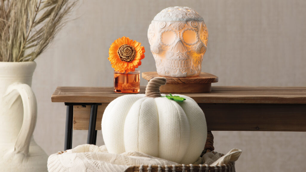 Scentsy Calaverita White Skull Wax Warmer, Lumina Pumpkin Darling Décor Plush and a fall inspired fragrance flower sitting in a living room