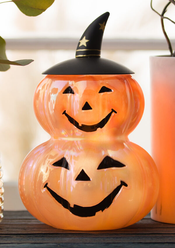 Scentsy Witch O’Lantern Wax Warmer sittin gon an entry table beside fall colored vases and a white pumpkin