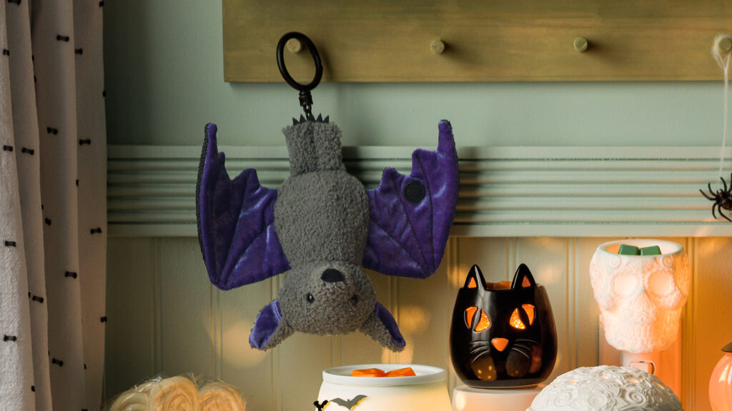 Batista the Bat Scentsy Buddy Clip hanging above an entry table beside Spooky Stare black cat mini wax warmer and the calaverita skill mini wax warmer