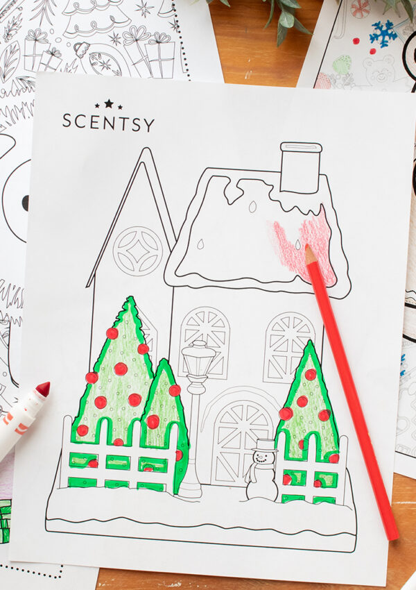 Scentsy holiday coloring pages for kids scattered on a table with markers, crayons and holiday scented wax melts