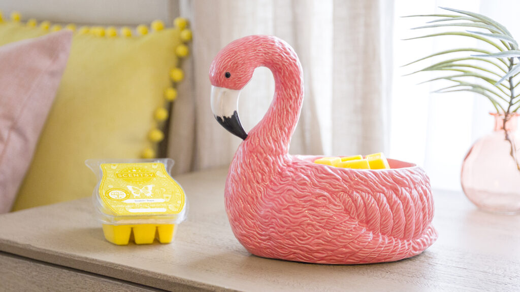 Pink flamingo wax warmer melting yellow wax melts on a bedroom side table