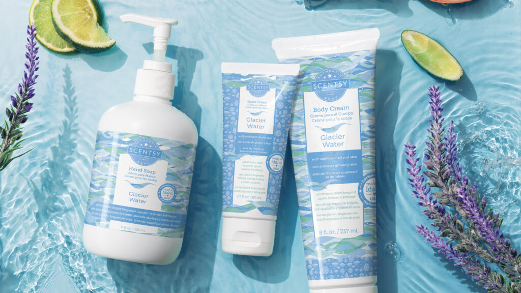 Scentsy body cream, hand cream and hand soap scented in glacier water fragrance laying on a blue water background with lavender sprigs and limes floating around the body products