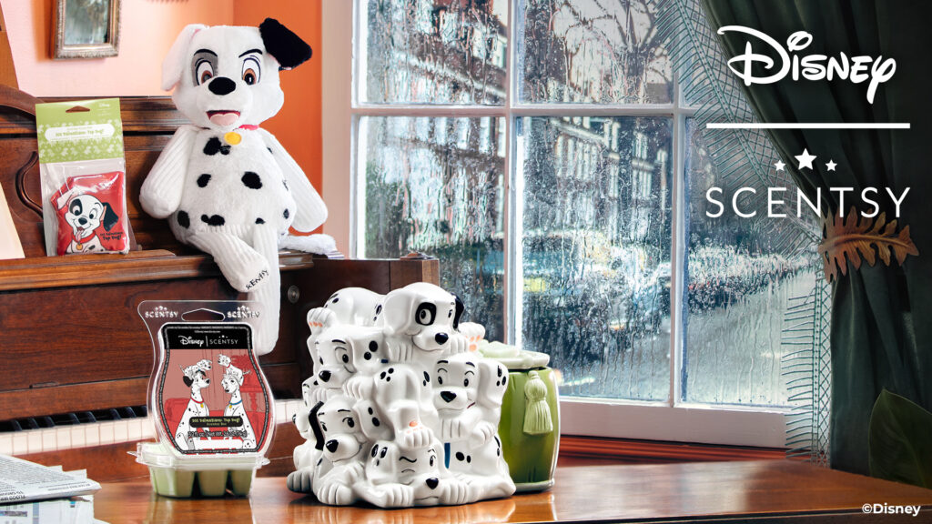 the Disney 101 Dalmatians scentsy products sitting on a piano in front of a rainy window including a scent pack, wax warmer, Spot the dalmatian scentsy buddy stuffed animal and wax bar inspired by the disney movie