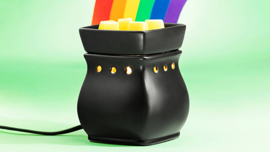 Scentsy black satin curved wax warmer lit up welting yellow wax cubes with a rainbow in the background coming out of it