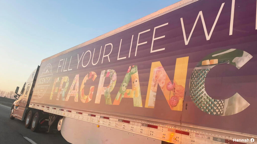 Scentsy’s colorful trailer semi truck cruising on the highway across America