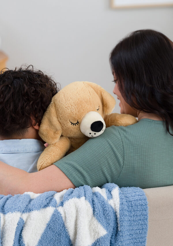 A mother and her son sitting on a couch cuddling a scentsy buddy