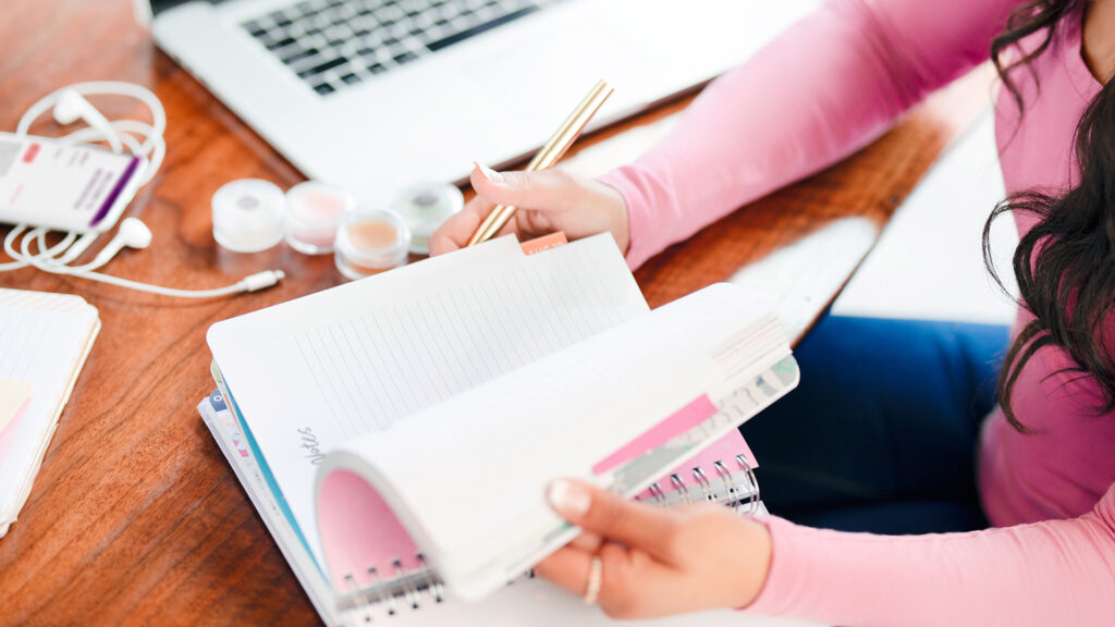 A photo of a woman looking through a planner, getting ready to write notes about Scentsy fragrances.