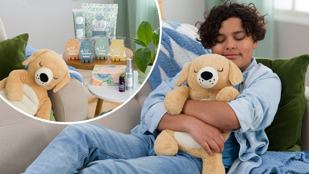 A young boy holds the Truman the Terrier Scentsy Weighted Buddy to his chest as he practices mental health breathing exercises.