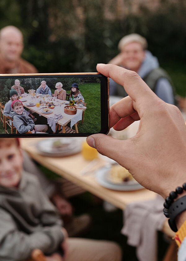 When family gathers for a reunion use Scentsy's tips to make the most of the event. In this image, a person takes a digital photo of people gathered at a picnic table.