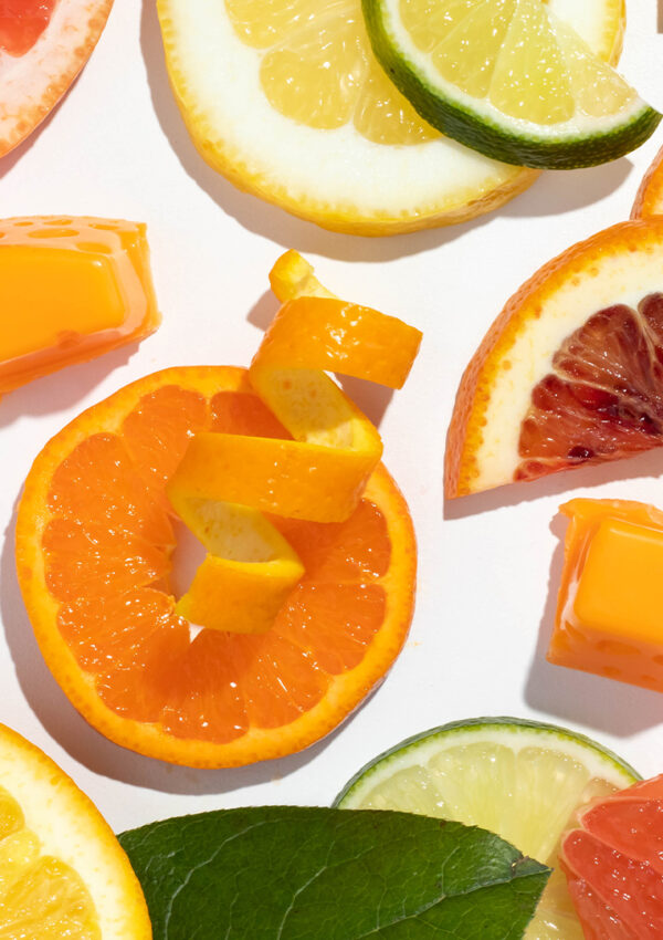 A bounty of different sliced citrus fruit, seen from above, covers a white surface.