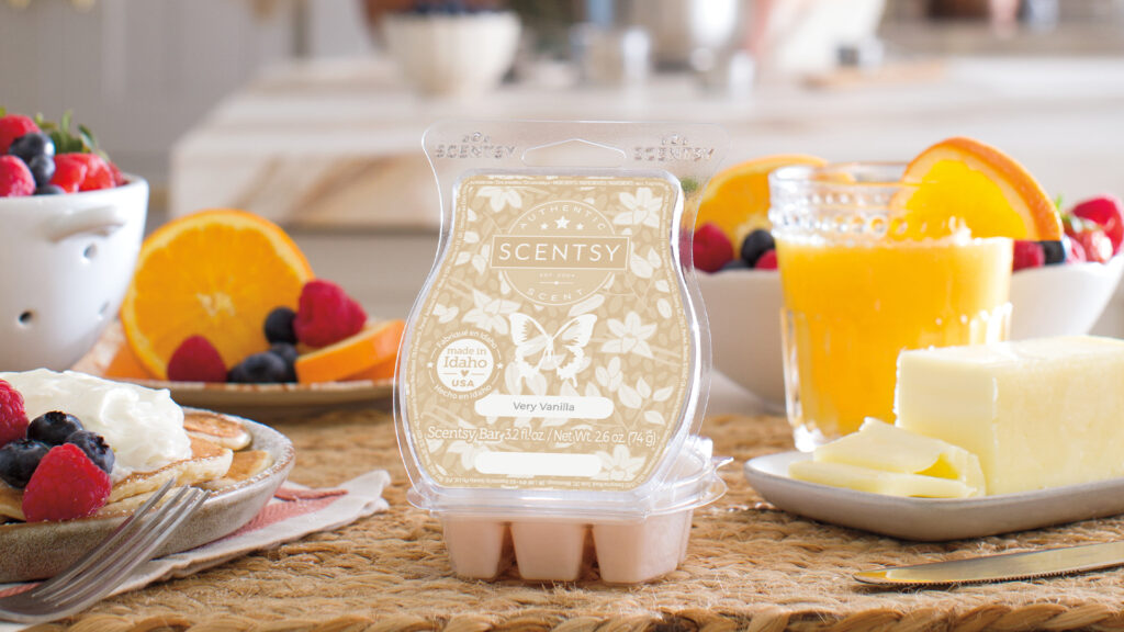 Scentsy Very Vanilla wax bar displayed on a table surrounded by fragrance notes of citrus fruits and sweet breakfast foods.