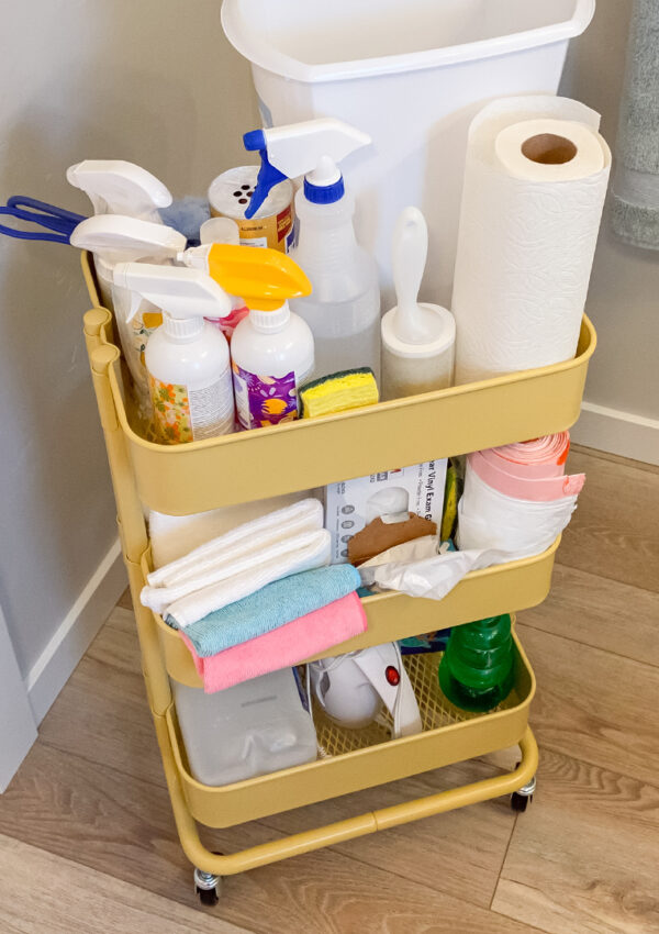 A triptych featuring, on the left, a pair of gloved hands cleaning tile with Scentsy Bathroom cleaner; the center image is a cleaning cart full of cleaning supplies; and the right image is a bottle of Scentsy All Purpose Cleaner.
