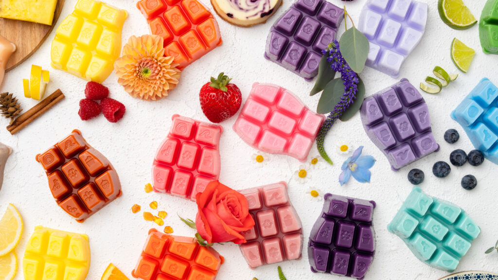A variety of different Scentsy wax bars with fruits and floral decorations among them to depict fragrance notes.