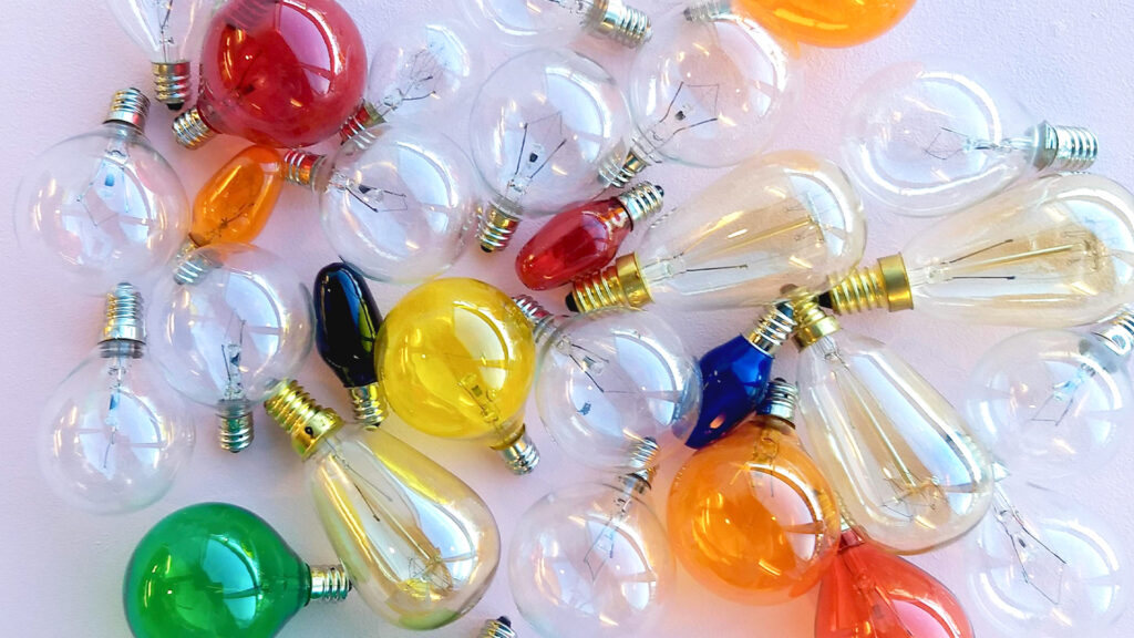 A clutter of Scentsy light bulbs of various colors and opacity on a table.