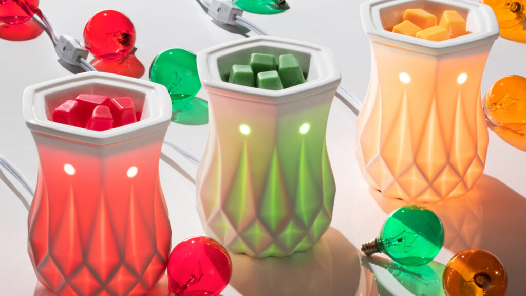 Three Scentsy Alabaster warmers lit with a red, green, and standard light bulbs.