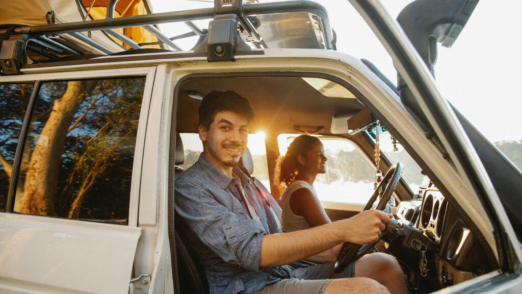 A couple sits together in a clean car, smiling with anticipation for an upcoming road trip.