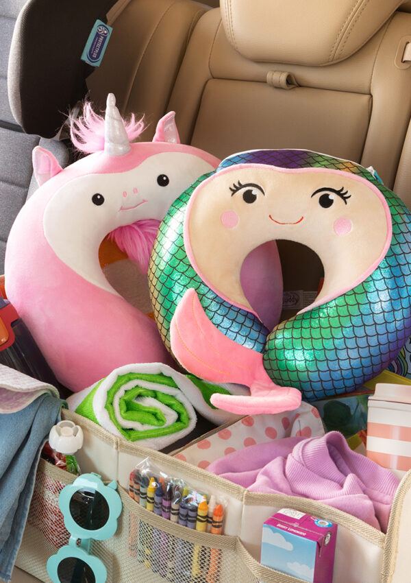 Scentsy buddies, neck pillows, and other scentsy summer product placed in the back seat of a car ready to go on a road trip.