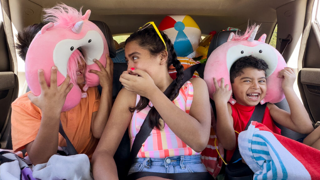 Children crowd into a back seat wearing Scentsy neck pillows