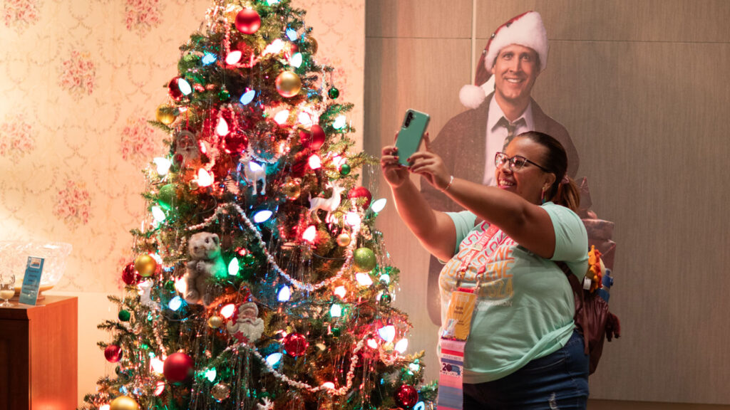 A Scentsy Consultant uses her phone to take a photo of a Christmas tree and holiday decor display at SFR 2024.