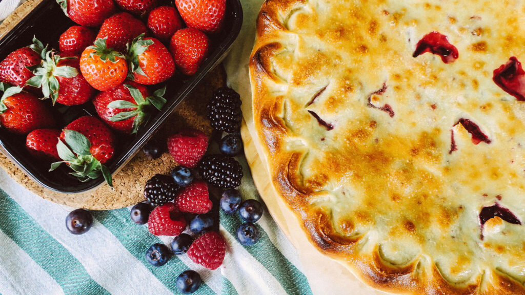 Berry pie sitting on a table with fresh berries next to it.