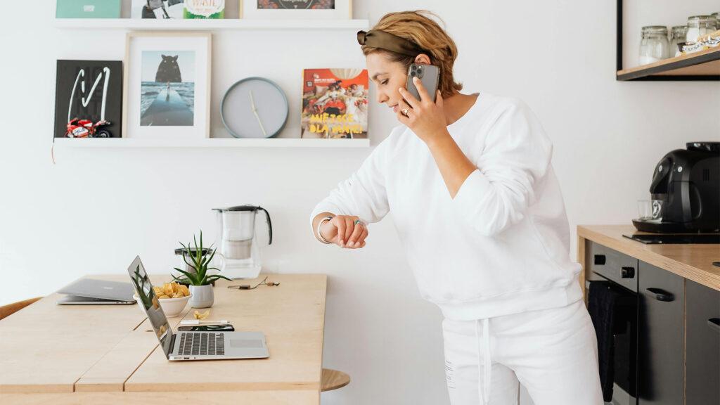 A woman works on her computer and talks on the phone