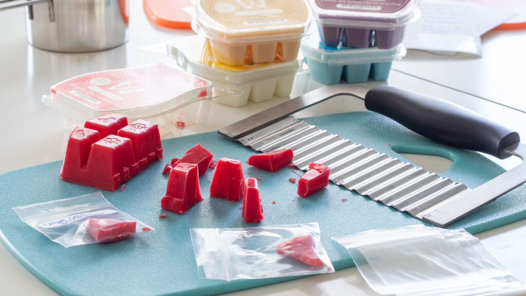 A Scentsy wax bar being cut and placed into small plastic bags.