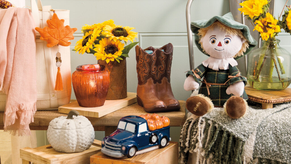 A photo of Scentsy's fall lineup of warmers and buddies arranged around sunflowers, pumpkins, and other seasonal decor.