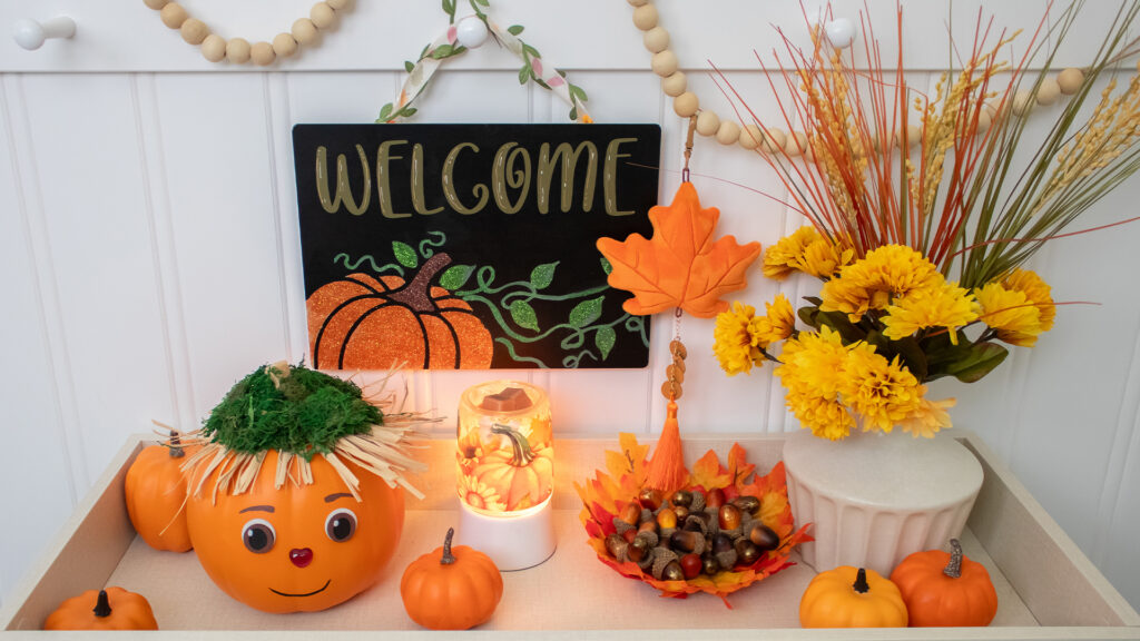 A table filled with flowers, pumpkins and similarly themed harvest and halloween decorations.