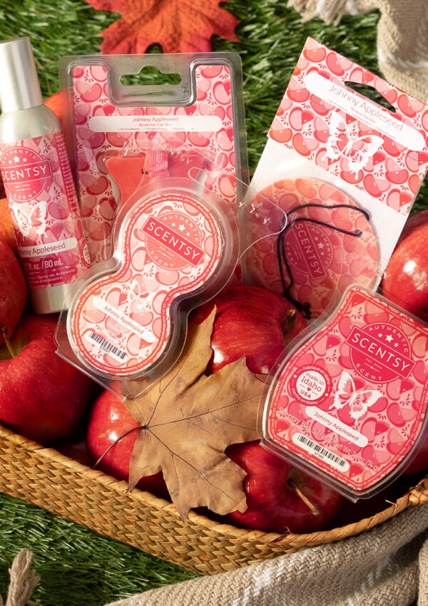 A basket packed with Scentsy Johnny Apple Seed fragrance products, fresh apples, and fall leaves.