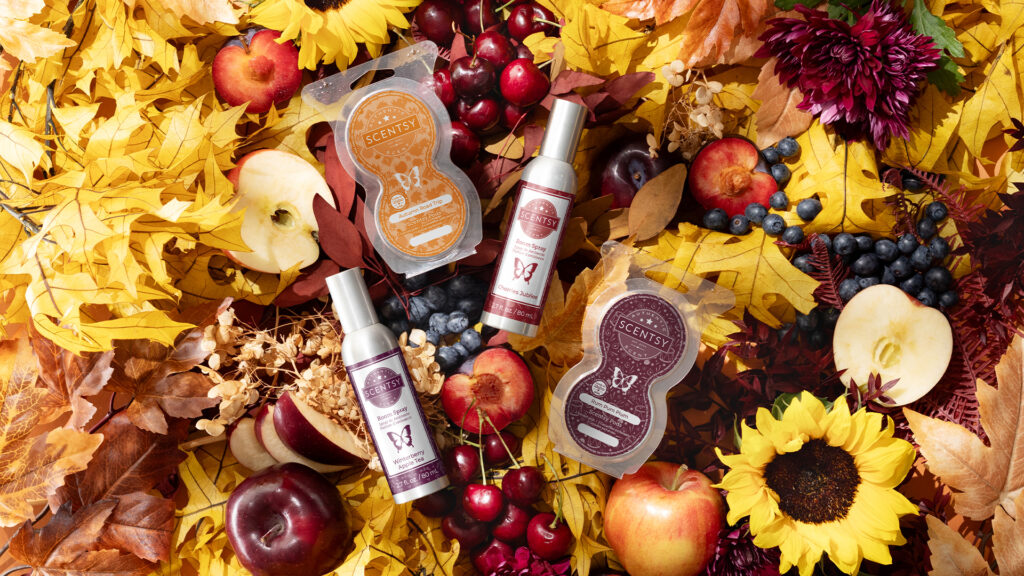 Scentsy pods and room sprays from the fall harvest collection surrounded by colorful fall leaves, fruits and berries, and sunflowers.